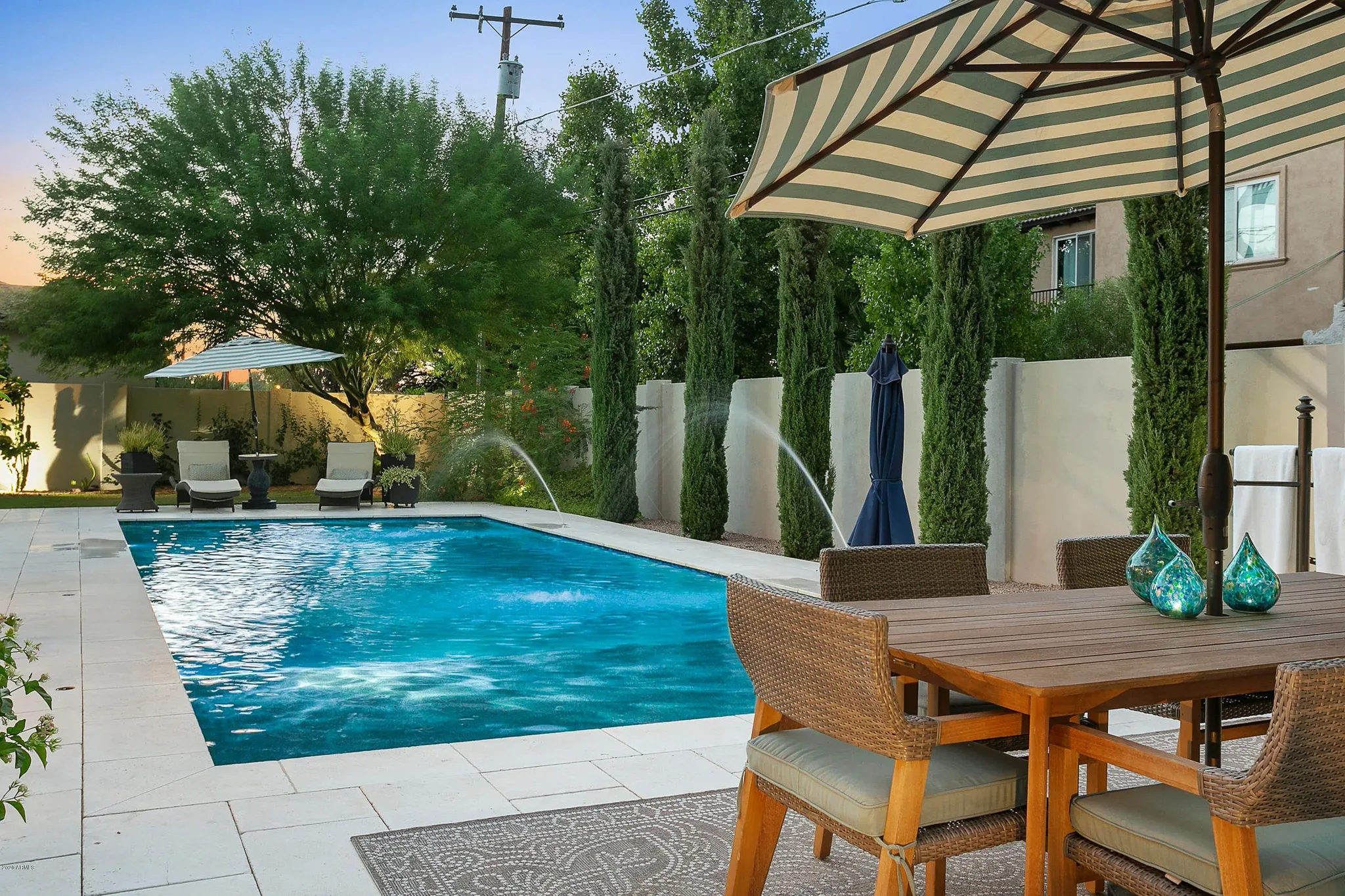 A backyard with a pool and patio furniture.